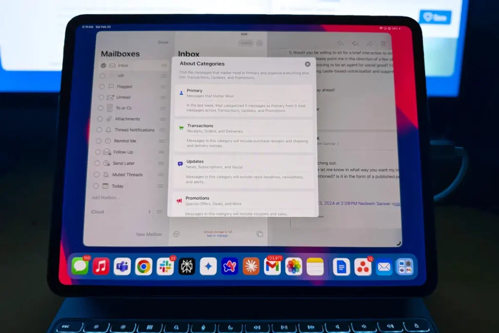 Pembaruan Apple Mail di macOS 15.4 dan iPadOS 18.4 yang Akan Mengubah Pengalaman Anda 2 Layar tablet menunjukkan aplikasi email yang menampilkan kategori seperti Utama, Transaksi, Pembaruan, dan Promosi di Kotak Masuk. Di bawah aplikasi, bilah alat menampilkan berbagai ikon aplikasi, dan perangkat terhubung ke keyboard.